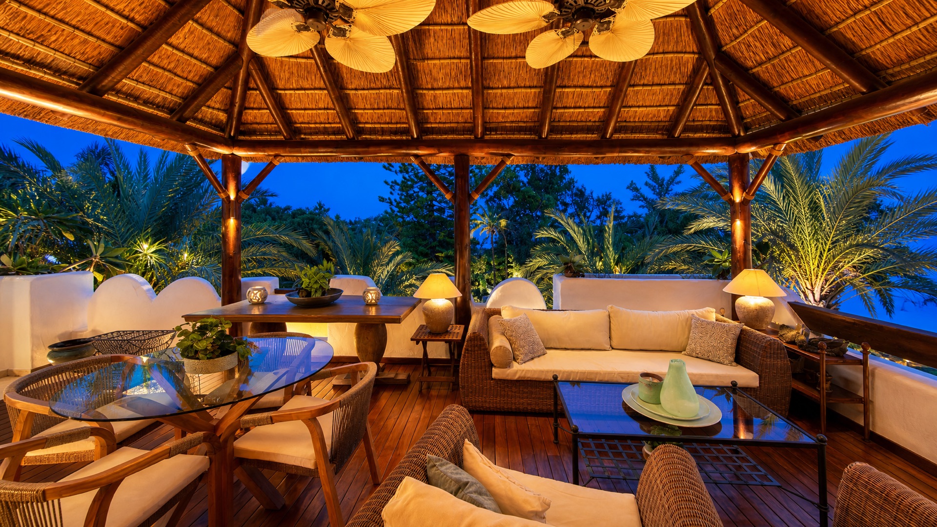 The same palapa terrace at dusk, lamps glowing