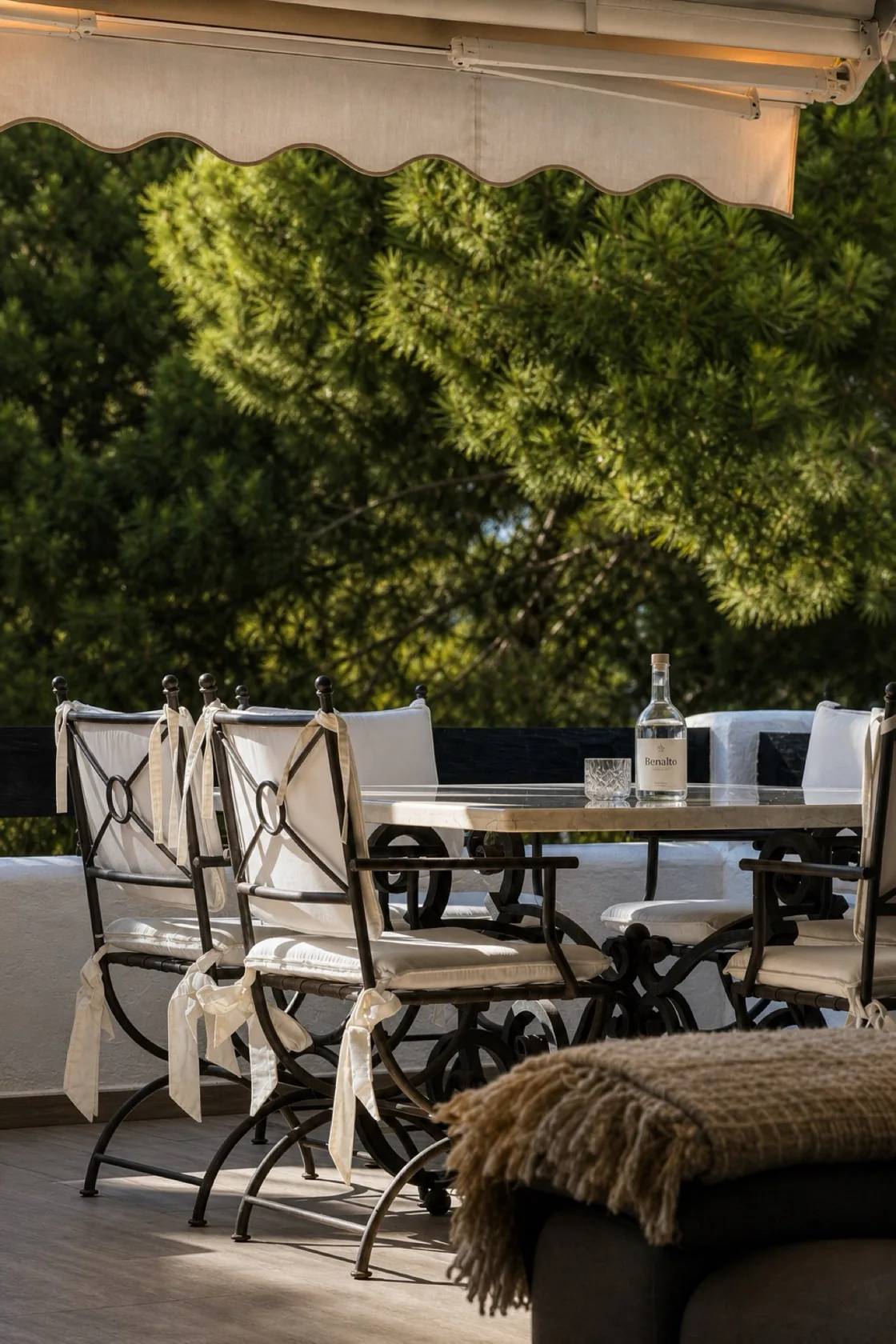 Terrace dining table and iron chairs under the awning at the La Isla penthouse